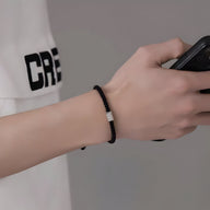 Bracelet cordon noir pour homme avec ornement cylindrique en argent, style moderne et épuré.
