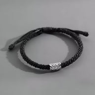 Bracelet cordon noir tressé avec ornement cylindrique en argent gravé pour homme.