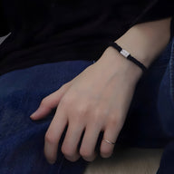 Bracelet cordon noir avec ornement cylindrique en argent, style masculin moderne.