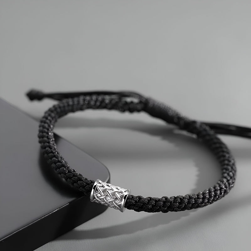 Bracelet cordon noir tressé avec ornement cylindrique en argent au design gravé.