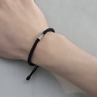 Bracelet cordon noir avec ornement cylindrique en argent, style masculin élégant.