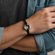 Bracelet cordon noir avec ornement hexagone en acier inoxydable porté au poignet.