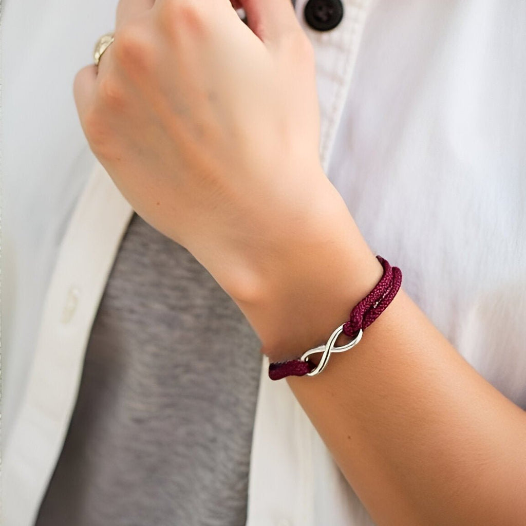 Bracelet cordon bordeaux ajustable avec ornement infini en métal argenté, style moderne.