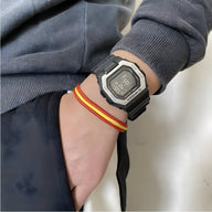 Bracelet cordon pays aux couleurs rouge et jaune avec manille en acier inoxydable porté au poignet.