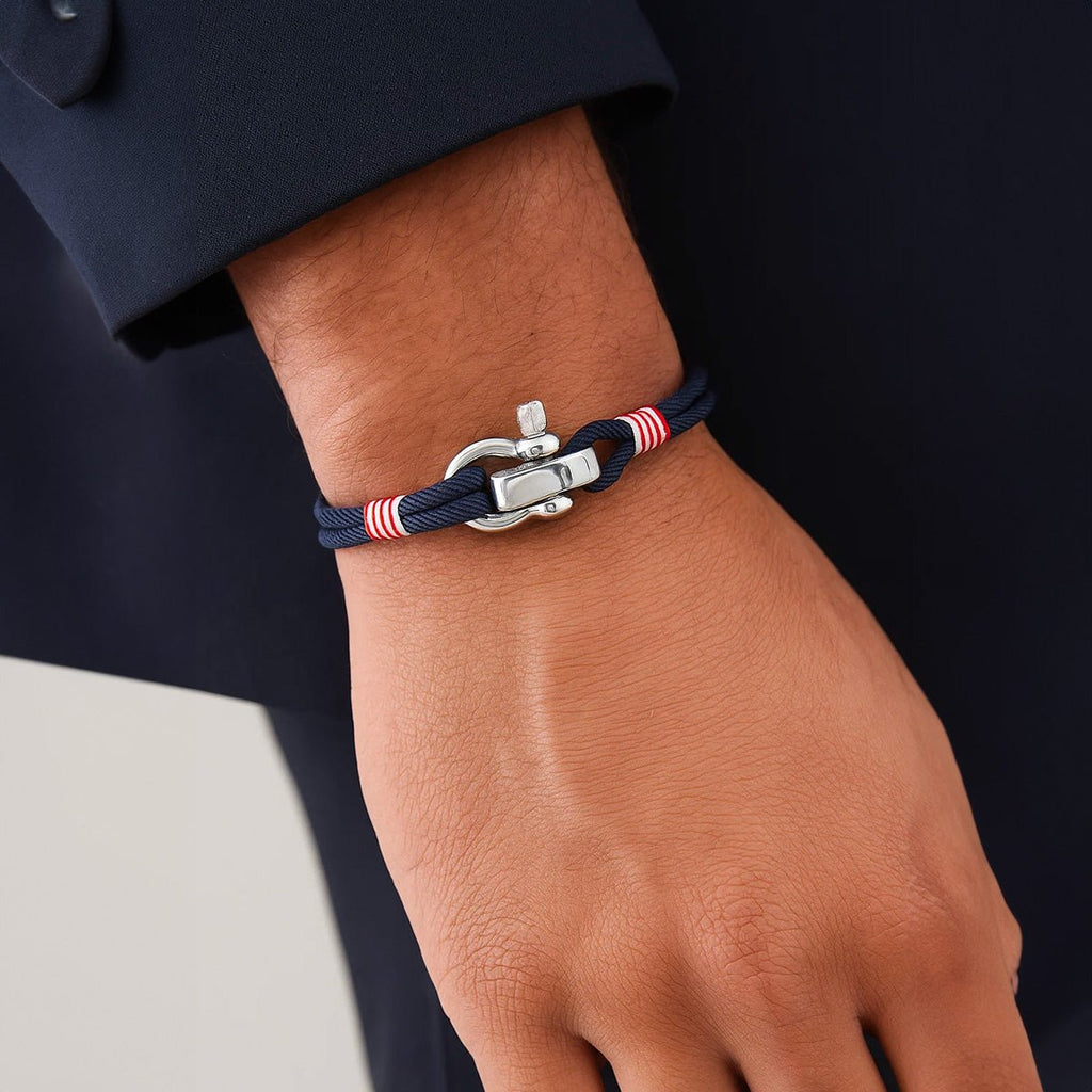 Bracelet cordon bleu marine avec manille en acier inoxydable et détails rouges et blancs.