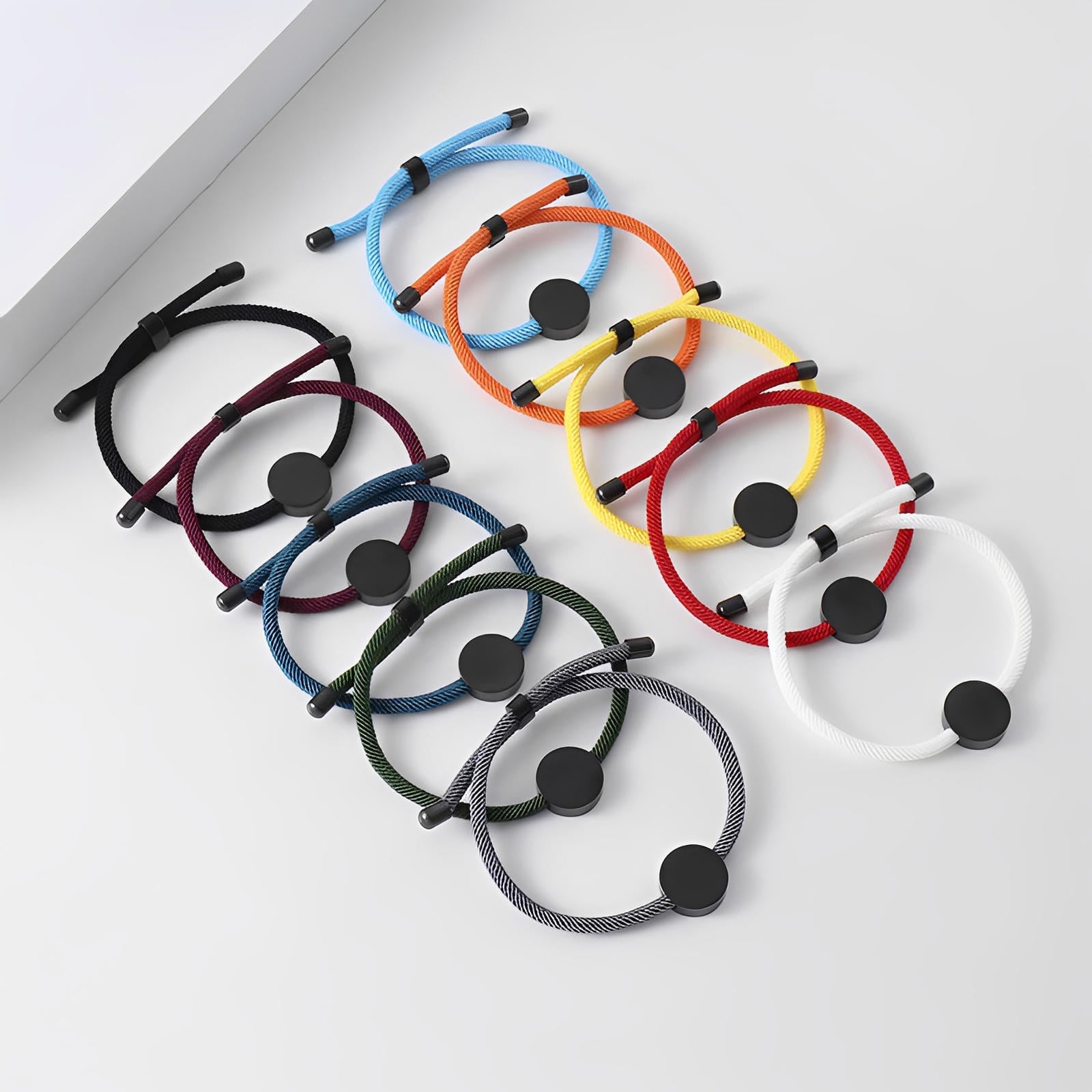 Bracelets cordon colorés avec médaillon rond en acier inoxydable, finition mate, design ajustable.