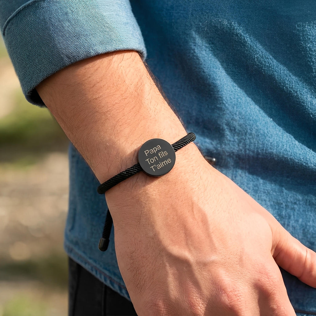 Bracelet cordon noir avec médaillon rond en acier inoxydable gravé, style minimaliste et ajustable.