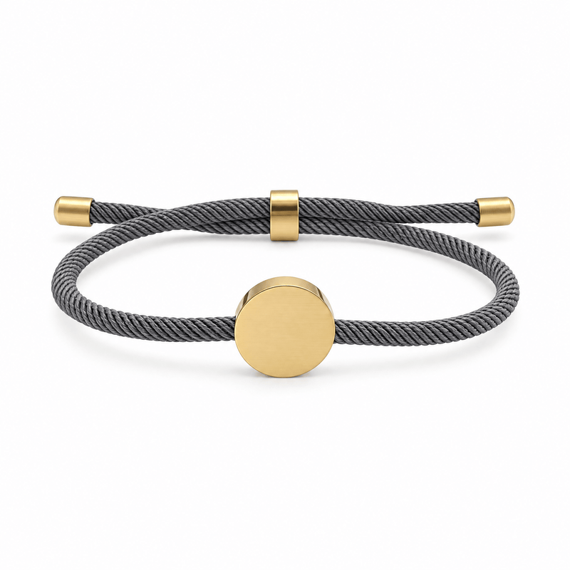 Bracelet Dax Or / Gris, cordon ajustable et médaillon rond, posé de face sur fond blanc
