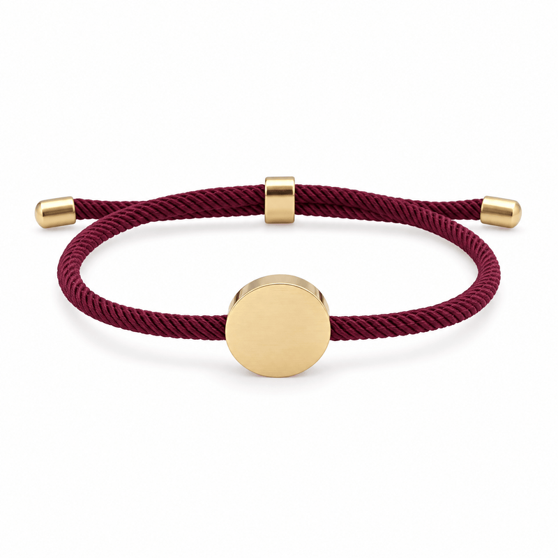 Bracelet Dax Or / Bordeaux, cordon ajustable et médaillon rond, posé de face sur fond blanc