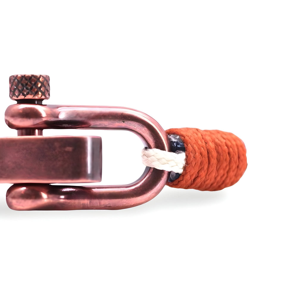 Bracelet cordon blanc avec extrémité orange et mousqueton ancien en métal cuivré.