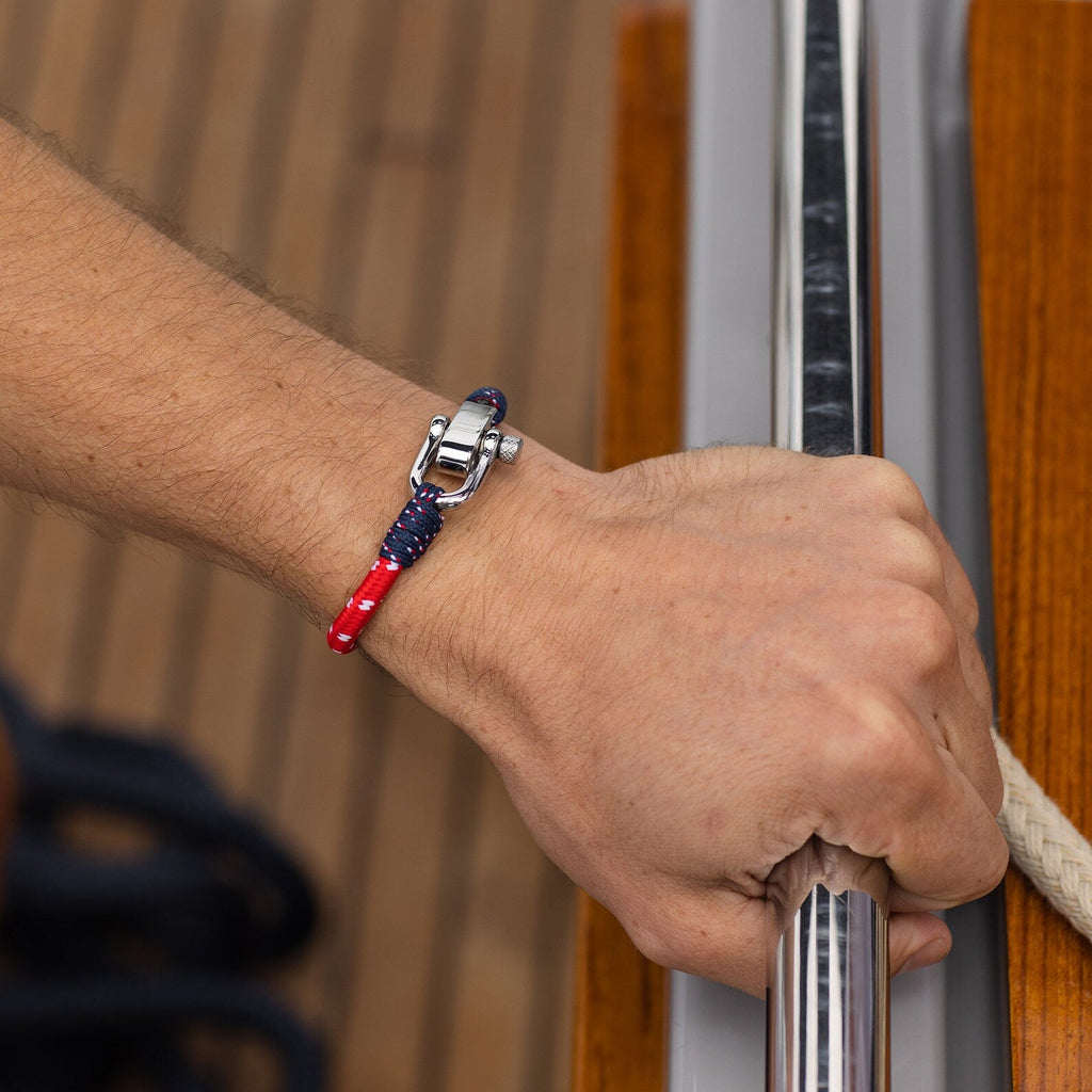 Bracelet cordon bleu et rouge avec mousqueton métallique brillant sur poignet homme.