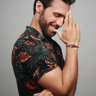 Bracelet cordon rouge et bleu à mousqueton porté par homme au poignet, style décontracté.