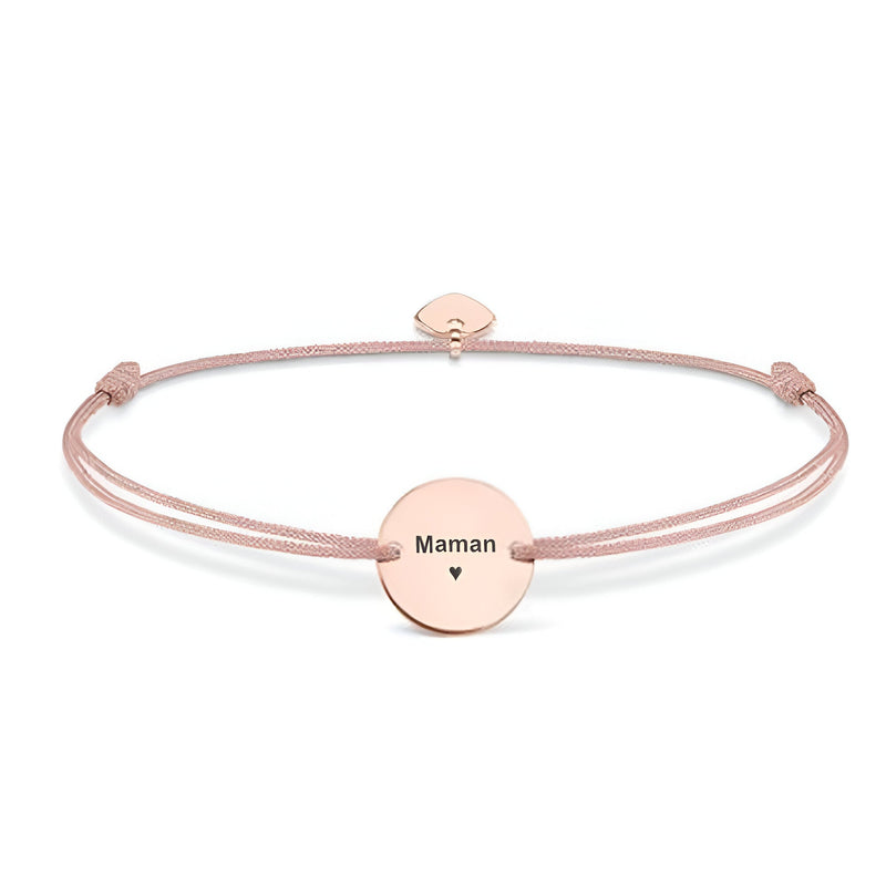 Bracelet cordon rose avec disque en acier inoxydable gravé "Maman" et petit cœur noir.