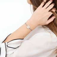 Bracelet cordon gris avec disque en acier inoxydable argenté, style minimaliste pour femme.