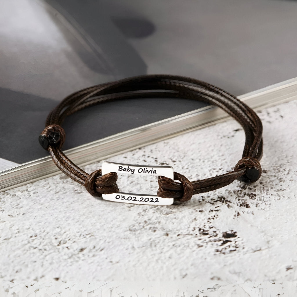 Bracelet cordon marron avec plaque en acier inoxydable gravée personnalisée et fermoir coulissant.