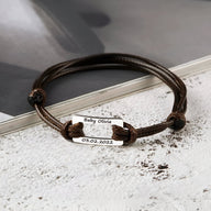 Bracelet cordon marron avec plaque en acier inoxydable gravée personnalisée et fermoir coulissant.