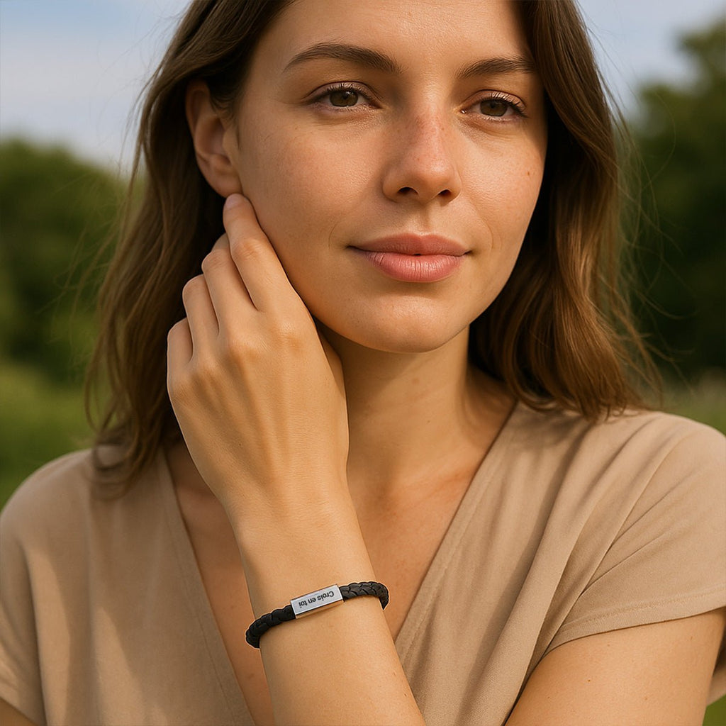 Bracelet cordon noir en cuir avec plaque personnalisée rectangulaire porté au poignet femme.