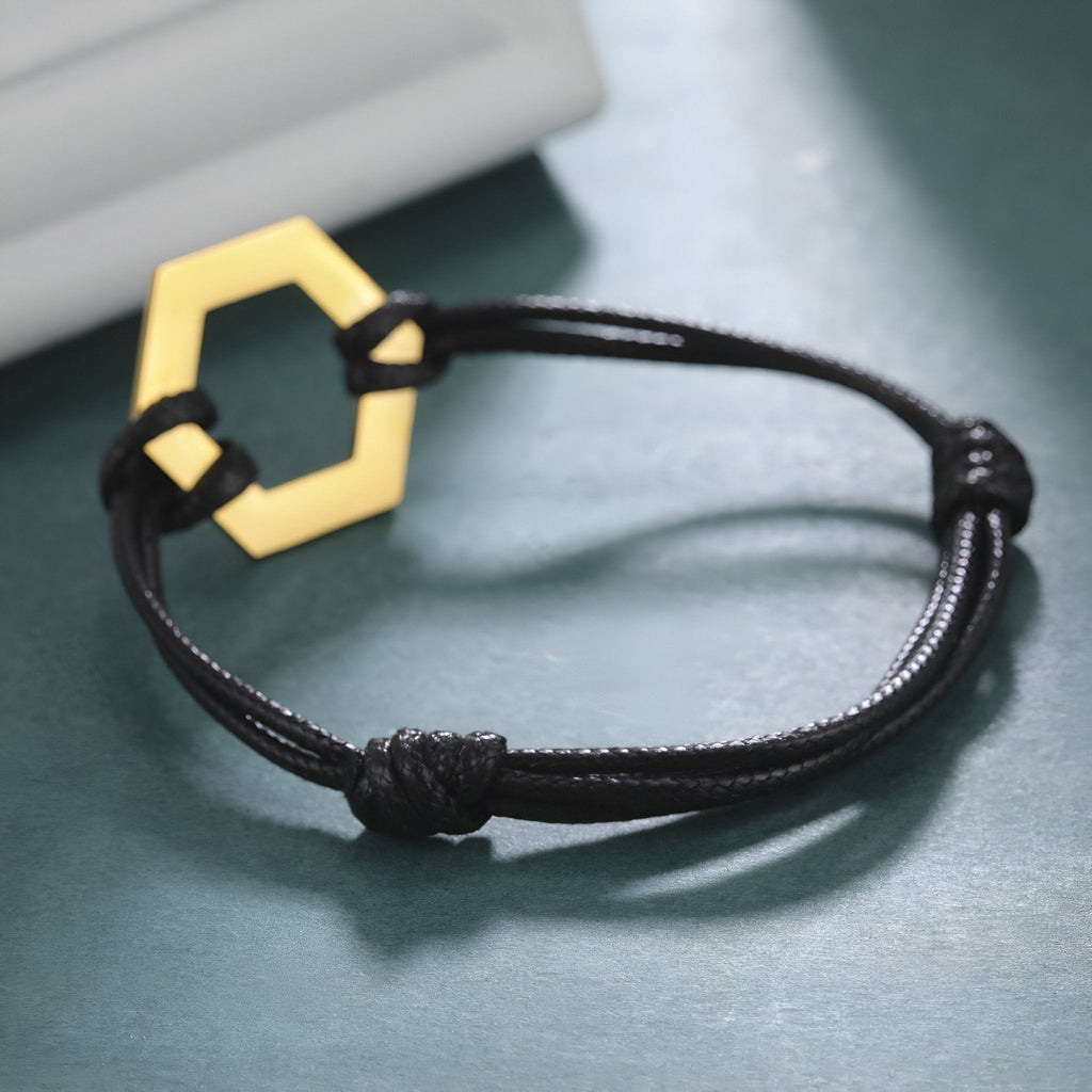 Bracelet cordon noir avec pendentif hexagone en acier inoxydable doré, style minimaliste femme.