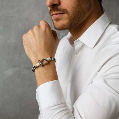 Bracelet cordon blanc et noir avec mousqueton arrondi en métal sur poignet masculin, style moderne et élégant.