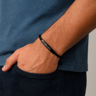 Bracelet cordon noir ajustable avec plaque longue en acier inoxydable porté au poignet homme.