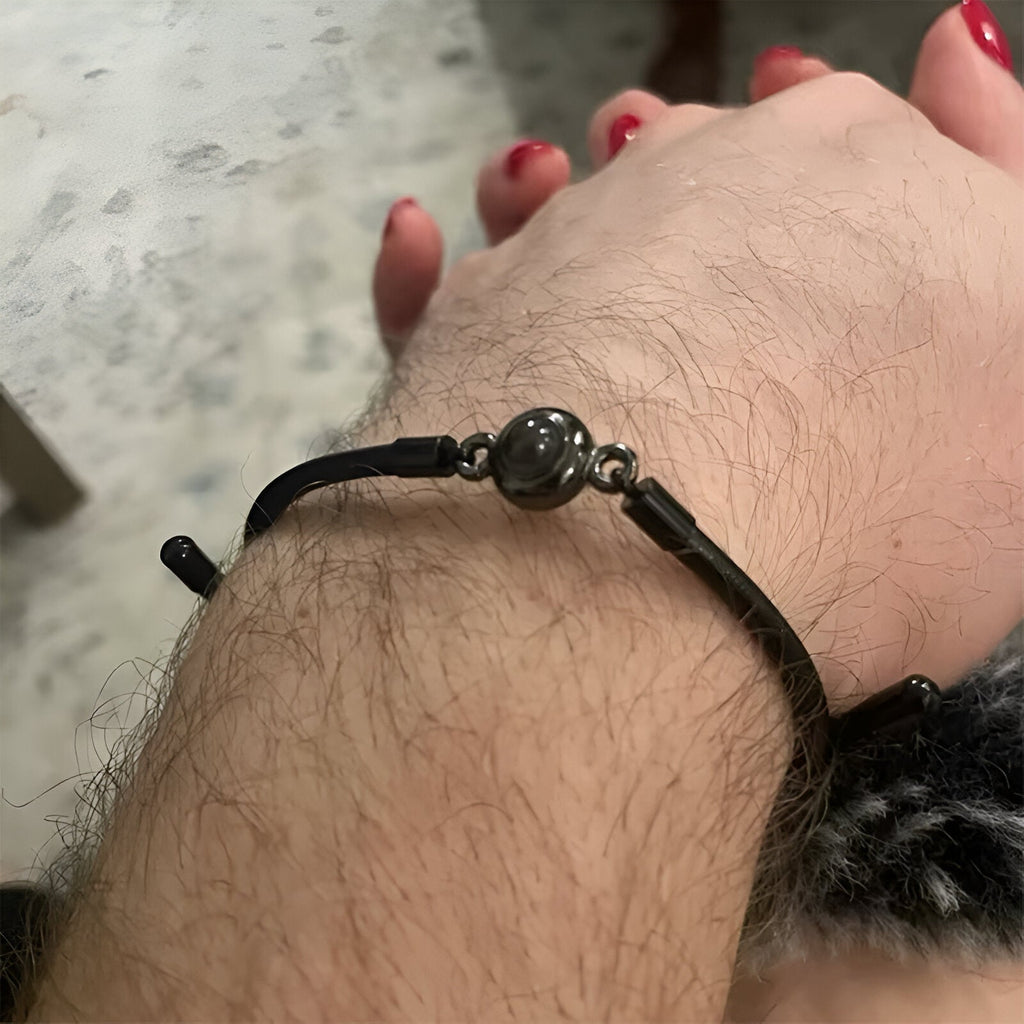 Bracelet en cuir noir tressé avec perle en acier inoxydable noir mat, fermé par crochet métallique noir.