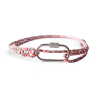 Bracelet cordon rose à motif multicolore avec mousqueton ovale en métal argenté texturé.