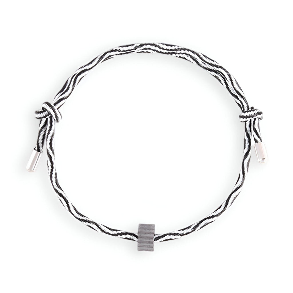 Bracelet cordon noir et blanc avec ornement tubulaire en carbure de tungstène gris.