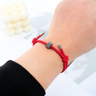 Bracelet cordon rouge avec ornement cylindrique en carbure de tungstène sur poignet féminin.