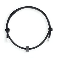 Bracelet cordon noir ajustable avec ornement cylindrique en carbure de tungstène gris anthracite.