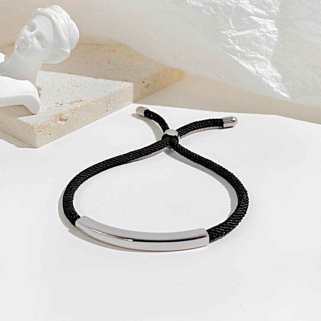 Bracelet cordon noir avec plaque gourmette en acier inoxydable, style épuré et moderne.
