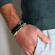 Bracelet cordon vert avec mousqueton argenté porté avec bracelet de perles vert clair.