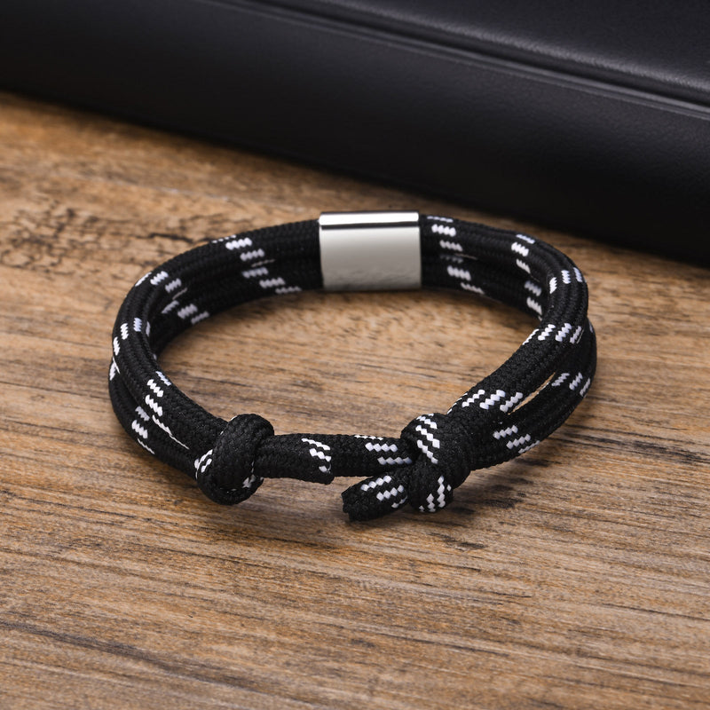 Bracelet cordon noir à rayures blanches avec fermoir métallique argenté pour homme.
