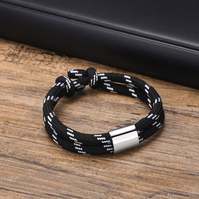 Bracelet cordon noir rayé blanc avec fermoir métallique argenté, style masculin.