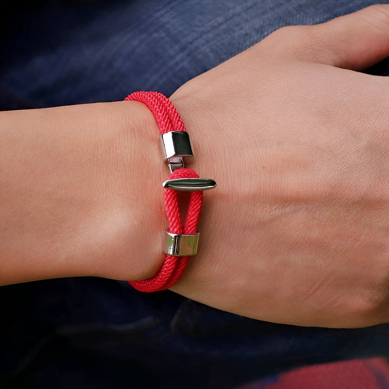 Bracelet cordon rouge en coton avec fermoir métal argenté sur poignet homme.