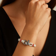 Bracelet cordon blanc avec manille en acier inoxydable, détails rouges, style moderne et épuré.