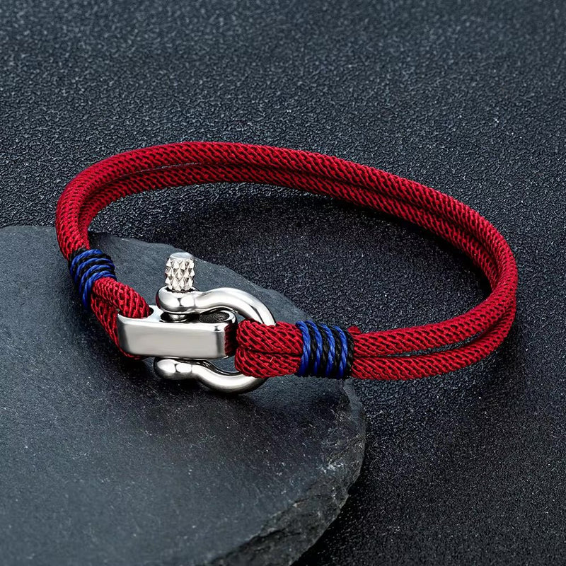 Bracelet cordon rouge bordeaux avec manille en acier inoxydable et nœuds bleus marines ajustables.