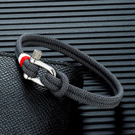 Bracelet cordon noir pour homme avec manille en acier inoxydable et détail rouge blanc.