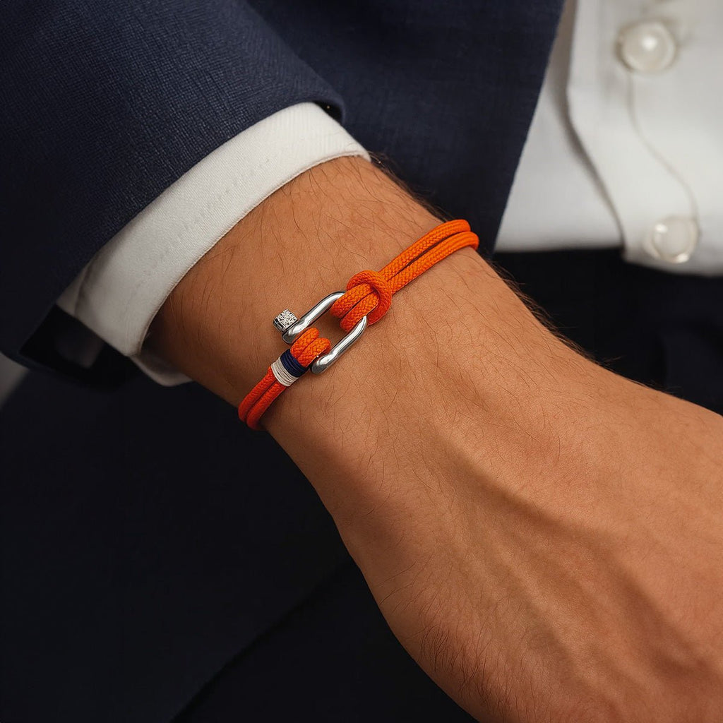 Bracelet cordon orange avec manille en acier inoxydable sur poignet masculin, style moderne et élégant.