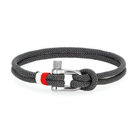 Bracelet cordon gris foncé avec manille en acier inoxydable et détail rouge sur le cordon.