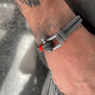Bracelet cordon gris avec mousqueton argenté et détail rouge, style masculin moderne.