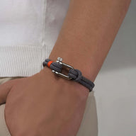 Bracelet cordon gris pour homme avec mousqueton argenté et nœud décoratif.