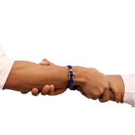 Bracelet cordon bleu avec mousqueton argenté porté sur poignet masculin en prise de main.