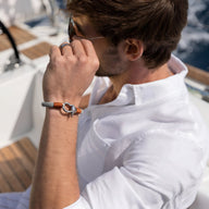 Bracelet cordon orange avec mousqueton arrondi en métal argenté porté par homme en chemise blanche.