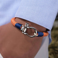 Bracelet cordon orange et bleu avec mousqueton arrondi en métal argenté, porté sur poignet<humanRights>.