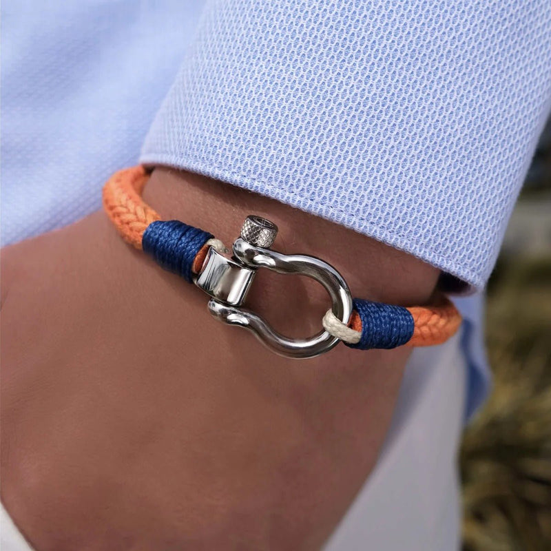 Bracelet cordon orange et bleu avec mousqueton arrondi en métal argenté, porté sur poignet<humanRights>.