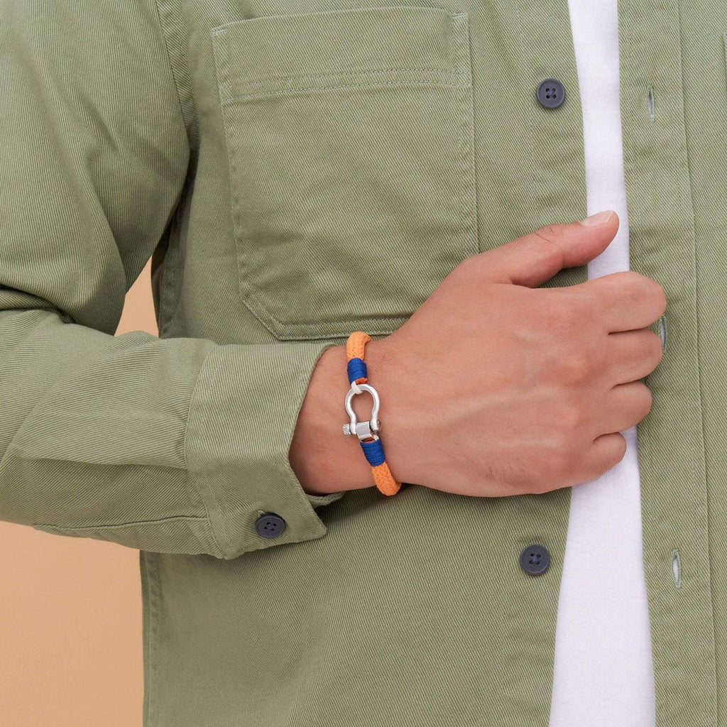 Bracelet cordon orange avec mousqueton arrondi en métal porté sur poignet masculin.