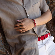 Bracelet cordon rouge pour homme avec mousqueton argenté porté au poignet.