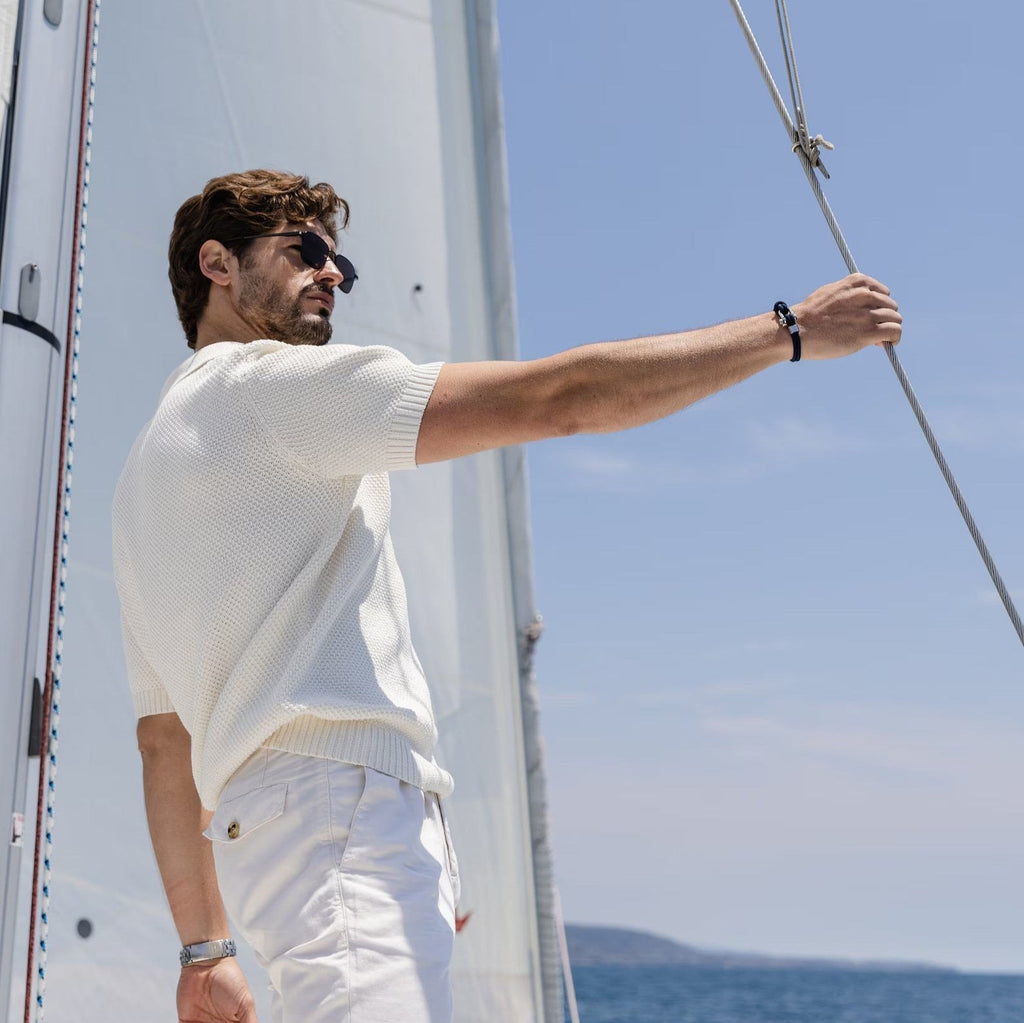 Bracelet cordon rouge pour homme avec mousqueton et détails argentés porté au poignet, style marin.