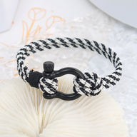 Bracelet cordon noir et blanc pour homme avec mousqueton noir mat et nœuds décoratifs.