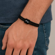 Bracelet cordon noir ajustable avec plaque acier inoxydable signe infini élégant.